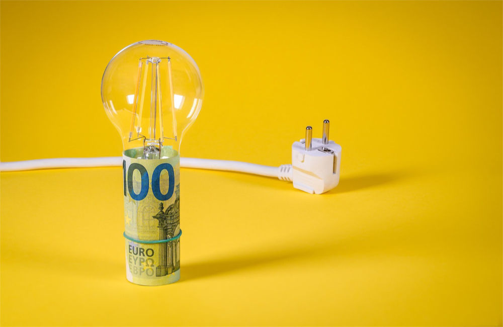 Glübirne mit Geldschein und Stromkabel - Energiekosten sparen